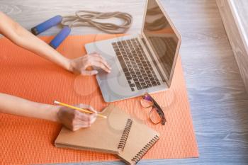 Young woman using laptop on yoga mat. Concept of balance between rest and work�