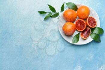 Plate with fresh blood oranges on color background�