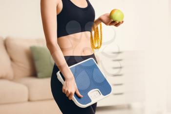 Woman with measuring tape, scales and apple at home. Weight loss concept�