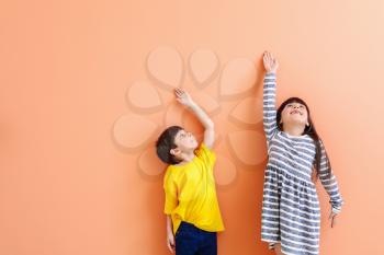 Cute little children measuring height near color wall�