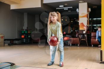Little girl playing bowling in club�