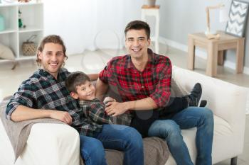 Happy gay couple with adopted child at home�