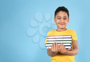 Portrait of cute little boy with books on color background�