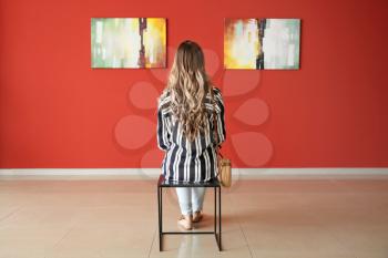 Woman sitting on chair in modern art gallery�