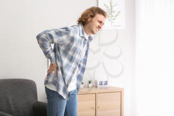 Young man suffering from back pain at home�