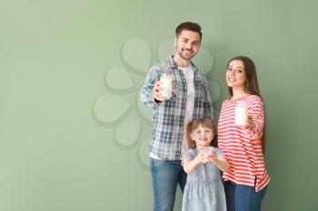Young family with glasses of tasty milk on color background�