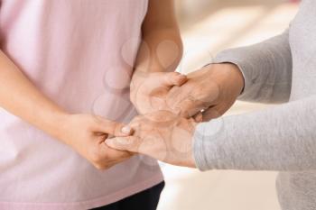 Young woman holding hands of her grandmother, closeup. Concept of care and support�