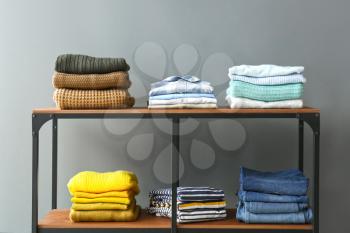 Stacked clothes on shelves against grey background�