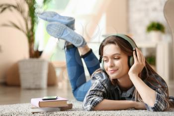 Beautiful young woman listening to audiobook at home�