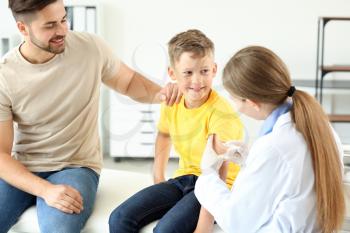 Doctor vaccinating little boy in clinic�