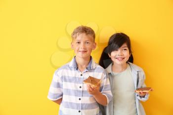 Funny little children with tasty toasts on color background�