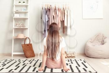 Young woman choosing clothes in her dressing room, back view�