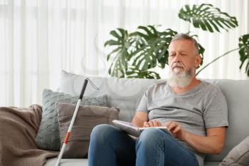 Blind mature man reading book written in Braille at home�