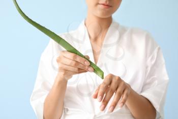 Beautiful young woman with aloe vera on color background�