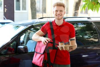 Worker of food delivery service near car outdoors�