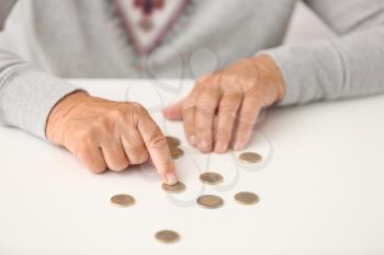 Elderly woman counting coins on table, closeup�