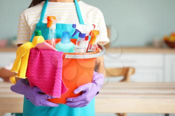 Woman with cleaning supplies in kitchen�