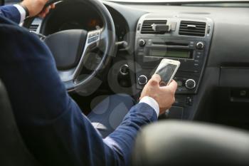 Successful businessman using mobile phone while driving modern car�