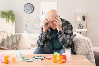 Elderly man with pills at home�