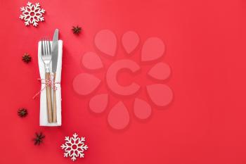 Clean cutlery with napkin and Christmas decor on color background�