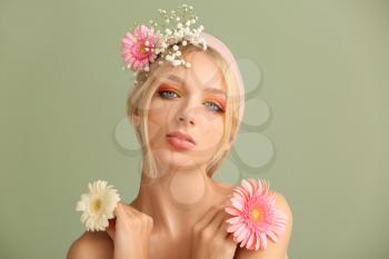Beautiful young woman with flowers on color background�