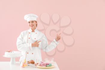 Female confectioner with tasty desserts on color background�