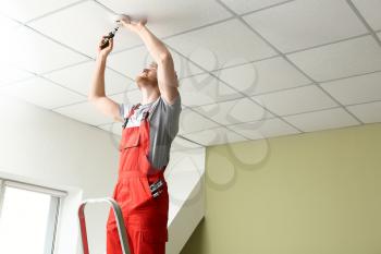 Electrician installing fire alarm system indoors�