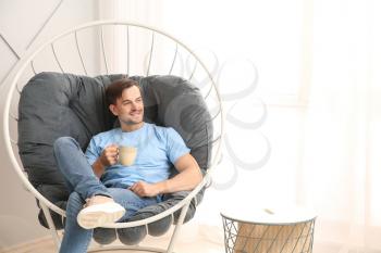 Handsome man drinking coffee while relaxing at home�