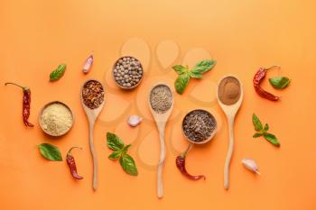 Bowls and spoons with different spices on color background�