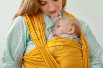 Young mother with little baby in sling on white background, closeup�