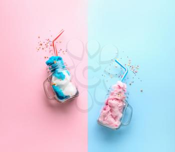 Jars with tasty cotton candy and sprinkles on color background�