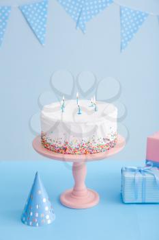 Tasty Birthday cake with gifts on table against color background�