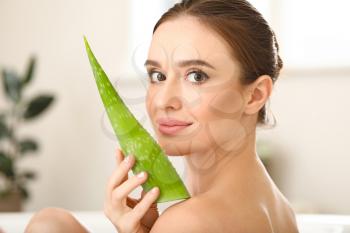 Beautiful young woman using aloe vera in bathroom�