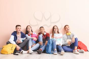Portrait of teenagers sitting near color wall�