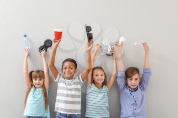 Little children with different trash on light background. Concept of recycling�