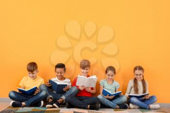 Cute little children reading books on color background�