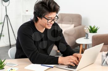 Asian programmer working on laptop in office�