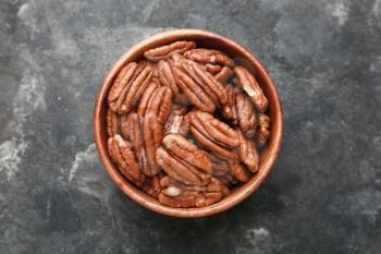 Bowl with tasty pecan nuts on dark background�