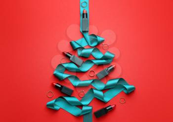 Beautiful Christmas tree made of lipsticks, rings and ribbon on color background�