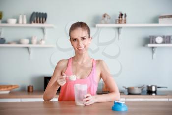 Sporty young woman making protein shake at home�