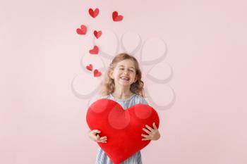 Cute little girl with pillow in shape of heart on color background. Valentines Day celebration�