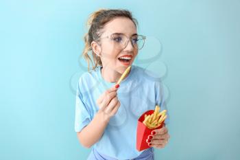 Portrait of beautiful young woman with french fries on color background�