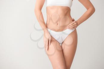 Beautiful young woman in underwear on light background. Concept of plastic surgery�