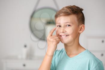 Little boy putting in contact lens at home�