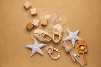 Baby booties with toys on color background�