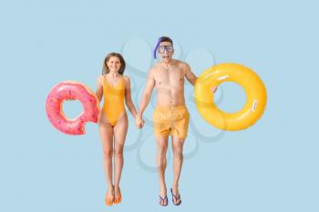 Jumping young couple with inflatable rings on color background�
