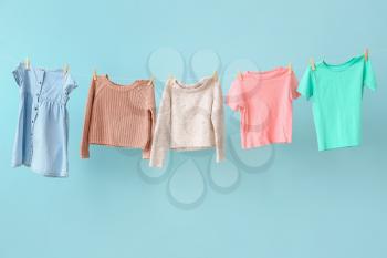 Clean laundry hanging on line against color background�