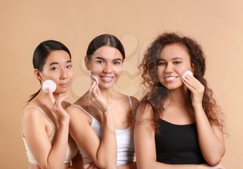 Beautiful young women with cotton pads on color background�