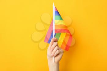Female hand with rainbow flag on color background. LGBT concept�