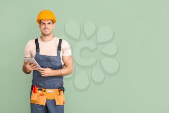 Handsome male worker with tablet computer on color background�